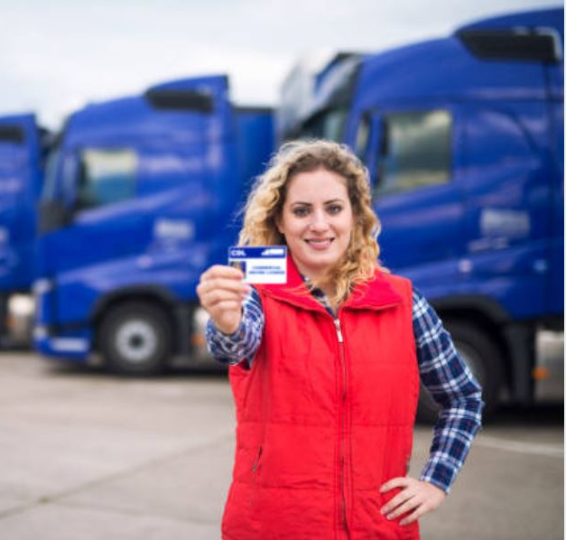 A woman holding up her credit card in front of some trucks.